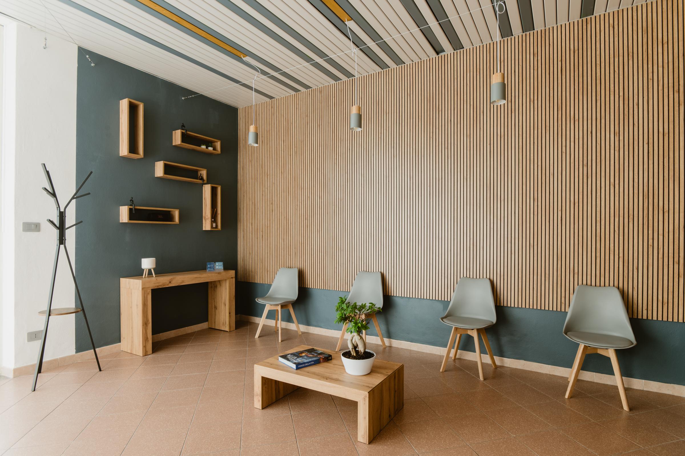 Studio F.N., sala d’attesa con parete a listelli, sedute e illuminazione sospesa